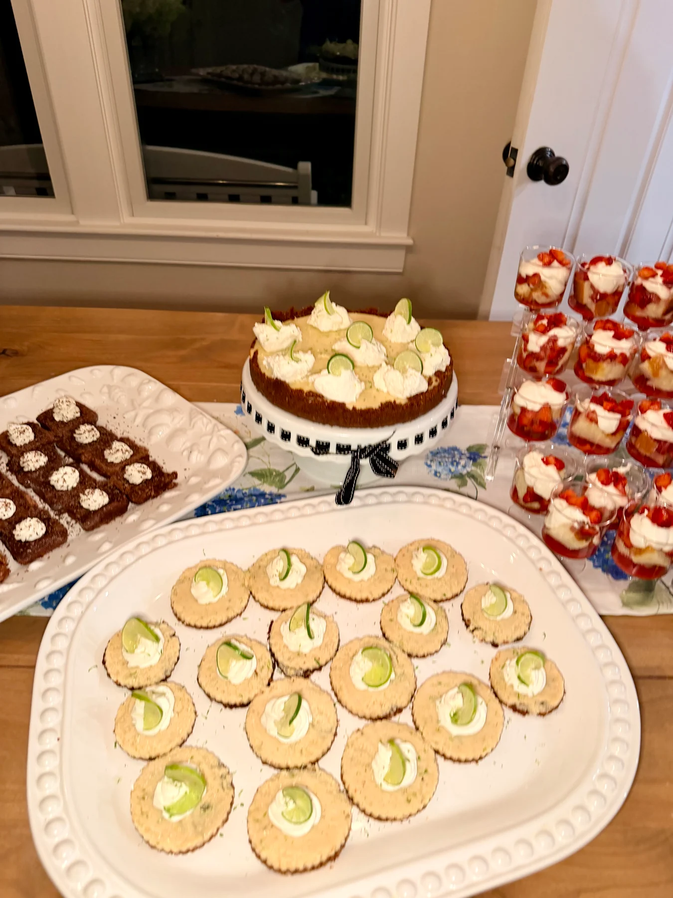 A dessert table with lime-garnished tartlets, strawberry dessert cups, and chocolate bites